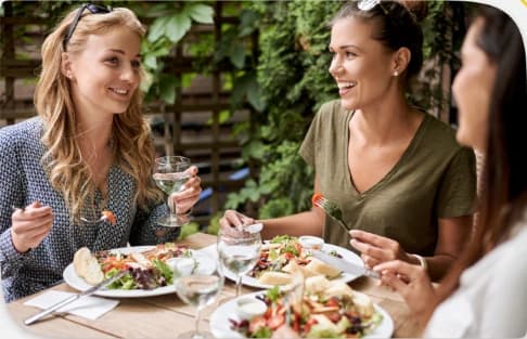 Trois amies partagent un repas en terrasse