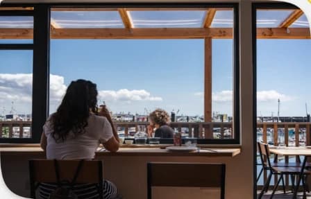 Vacanciers attablés au comptoir d’un bar Avolo face au port